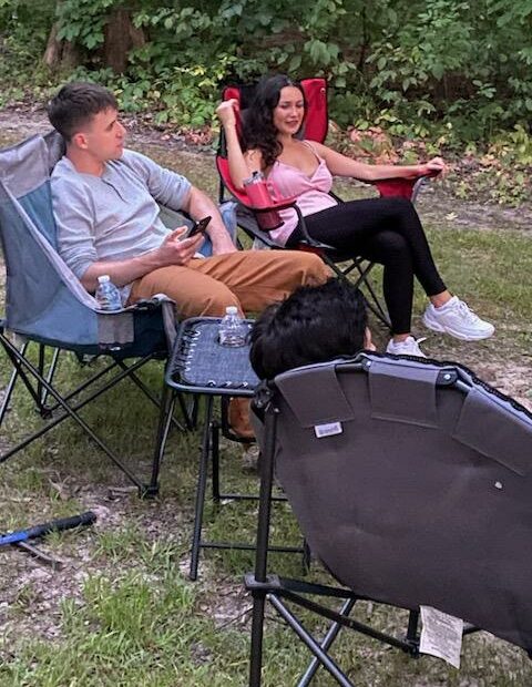 Two people relaxing in camping chairs outdoors